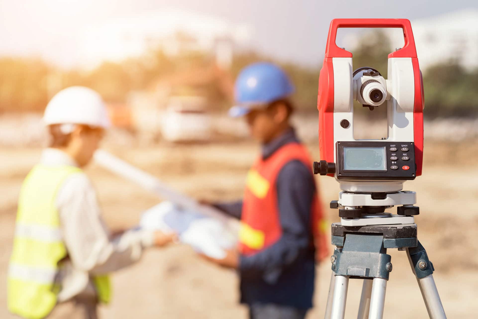 Surveyors With Level Camera At Construction Site