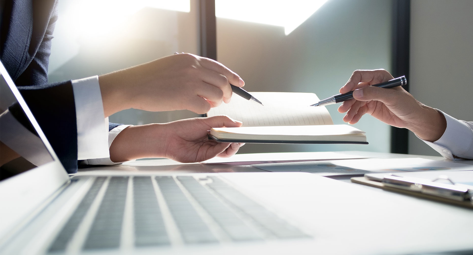 Two hands pointing at notebook